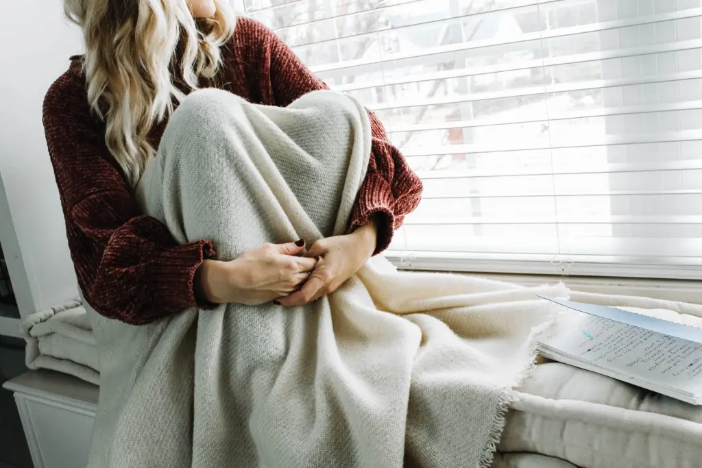 woman sitting on a home of wool bench cushion covered with a wool blanket