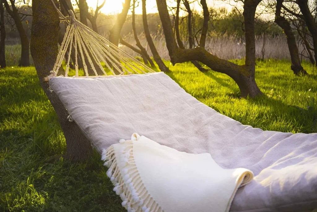 hammock with a natural wool cushion with a removable cover hung in a forest 