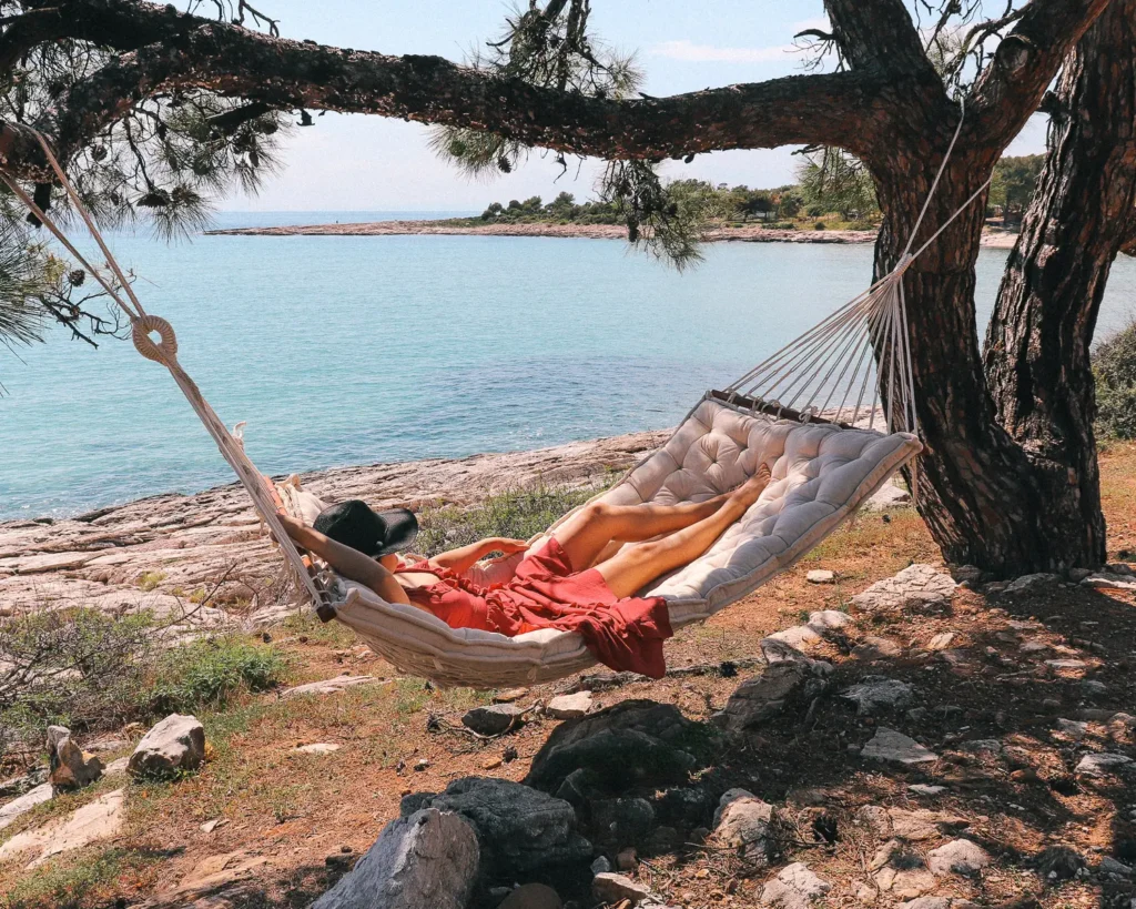 woman resting on a hammock with a wool cushion near the sea